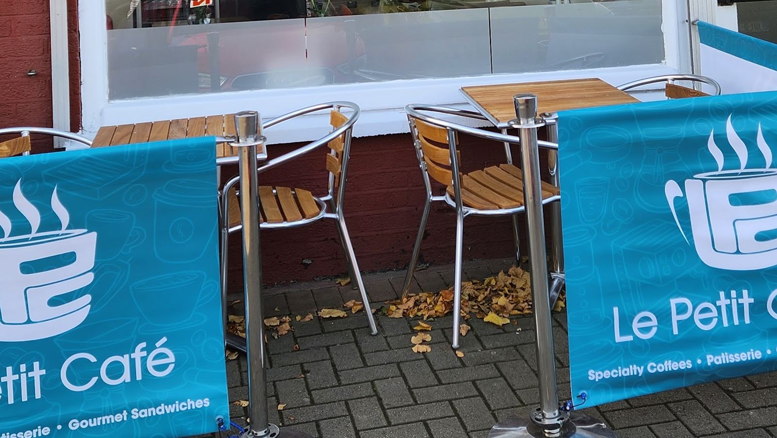 Outdoor tables and teal Le Petit Café banners outside the shop on St Pappin's Road